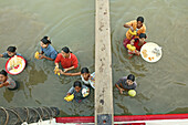 Selling snacks to passengers, Birds-eye view from boat of women standing waist high in river carrying trays of food, fruit on their heads to sell to boat passengers, Verkaeuferinnen, die bis zur Hüfte im Wasser stehen, tragen Obst auf deren Koepfe und ver