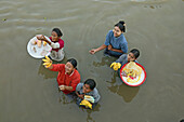 Selling snacks to passengers, Birds-eye view from boat of women standing waist high in river carrying trays of food, fruit on their heads to sell to boat passengers, Verkaeuferinnen, die bis zur Hüfte im Wasser stehen, tragen Obst auf deren Koepfe und ver