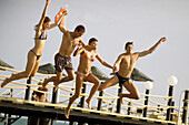Young people jumping from jetty