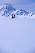 Two skier standing on snow hill, looking mountain panorama, Kuehtai, Tyrol, Austria