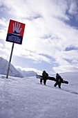 Two persons with snowboards leaving the safety area of slope, Kuehtai, Tyrol, Austria