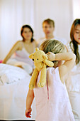 Toddler girl holding her teddy, rear view