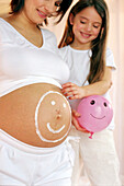 Mädchen berührt Bauch von schwangerer Mutter