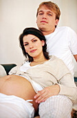 Man and pregnant woman on sofa, portrait