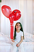 Girl holding red ballons