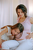 Girl listening to pregnant mothers stomach, close up