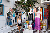 Girl passing a open clothes shop at shopping street, Mykonos-Town, Mykonos, Greece