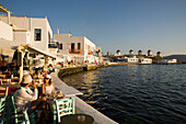 People sitting in restaurants and bars directly at sea, windmills in background, Little Venice, Mykonos-Town, Mykonos, Greece