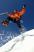 Young mountain climber jumping over snow