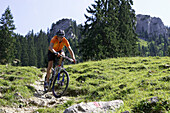 Mountainbiker downhill auf Schotterweg, Oberammergau, Deutschland