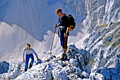 Father and son scrambling to the top of a rocky mountain. Summit of Amfiteater, Triglav Nationalpark, Julian Alps, Slovenia, Alps.