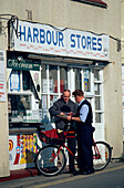 Ein Briefträger liefert Post vor ein Geschäft, Lyme Regis, Dorset, England