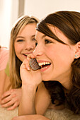 Weiblicher Teenager (14-16) telefoniert mit Handy, Freundinnen hören mit