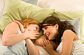 Two teenage girls (14-16) lying on bed in a whisper