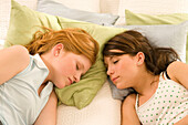 Zwei weibliche Teenager (14-16) liegen auf dem Bett und schlafen