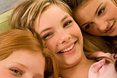 Three teenage girls (14-16) snuggling together on bed, close-up