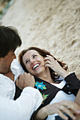 Couple in clothes embracing on beach, smiling