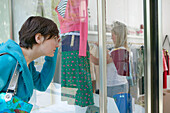 Young women looking at clothes in shop window