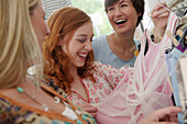 Young women looking at dresses and laughing in clothes shop