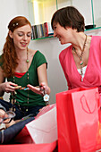 Young woman shows friend new belt in clothes shop