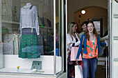 Junge Frauen beim Einkaufen treten aus einem Laden