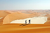 Young couple moving up Big Daddy. one of the earth highest dunes, Sossusvlei. Namib desert. Namibia. Africa