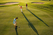 Golfers on golf course, long shadows