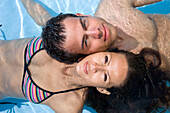 Junges Paar liegt im Swimming pool, Apulien, Italien