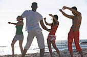 Group of young people exercising on beach with instructor, Apulia, Italy
