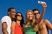 Four young people taking picture with camera phone, Apulia, Italy