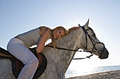 Young woman riding horse on beach, Apulia, Italy