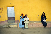 Ägyptische Menschen sitzen vor einer gelben Wand, Assuan, Ägypten