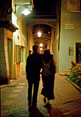 Couple walking trough old town at night, Bolzano, South Tyrol, Italy