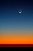 Crescent of moon above horizon after sunset