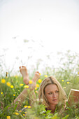 Young woman lying on meadow and reading book