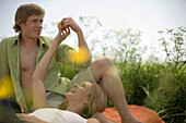 Couple having picnic on meadow, holding apple