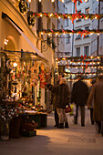 People standing in front of a shop at the christmassy decorated Goldgasse in the evening, Salzburg, Salzburg, Austria