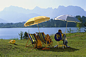 Family sunbathing at lake Barmsee, Krun, Werdenfelser Land, Bavaria, Germany