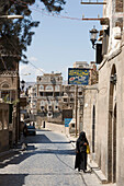 Frau geht entlang eine Straße in der Altstadt, Sana'a, Jemen