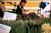 Gemüse, vor allem Spargel, am Markt in Venedig mit Verkäuferin im Hintergrund, Venezien, Italien