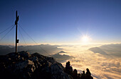 Menschengruppe am Gipfelkreuz des Grimming, Blick über das Nebelmeer im Ennstal und Gesäuse zur aufgehenden Sonne, Dachsteingruppe, Steiermark, Österreich