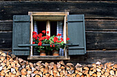 Window of a farmhouse with geraniums and wood pile, Gosau, Upper Austria, Austria