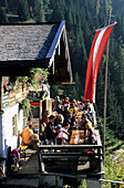 Alm with guests sitting on the sunny terrace, Chiemgau, Bavarian Alps, Salzburg, Austria
