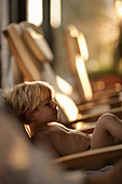 Young boy sitting in deckchair, Hotel Krallerhof, Leogang, Salzburger Land, Austria