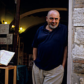 Weinhändler steht in der Tür seiner Weinhandlung, Montepulciano,Toskana, Italien