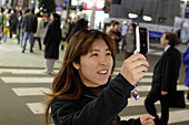Junge Frau mit Handy, Mobiltelefon, bei Nacht, ZebrastreifenEast Shinjuku, Tokio, Tokyo, Japan