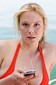 Young woman wearing red bikini, listening to portable MP3 player, Starnberger See, Upper Bavaria, Germany