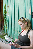 Woman leaning on boathouse, reading a book, Starnberger See, Upper Bavaria, Germany