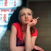 Young woman sitting on a sofa, smoking a cigarette