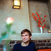 Mann sitzt im Café, Deutscher, Deutschland, verträumt, Blumen, schaut ins Leere, zuhören